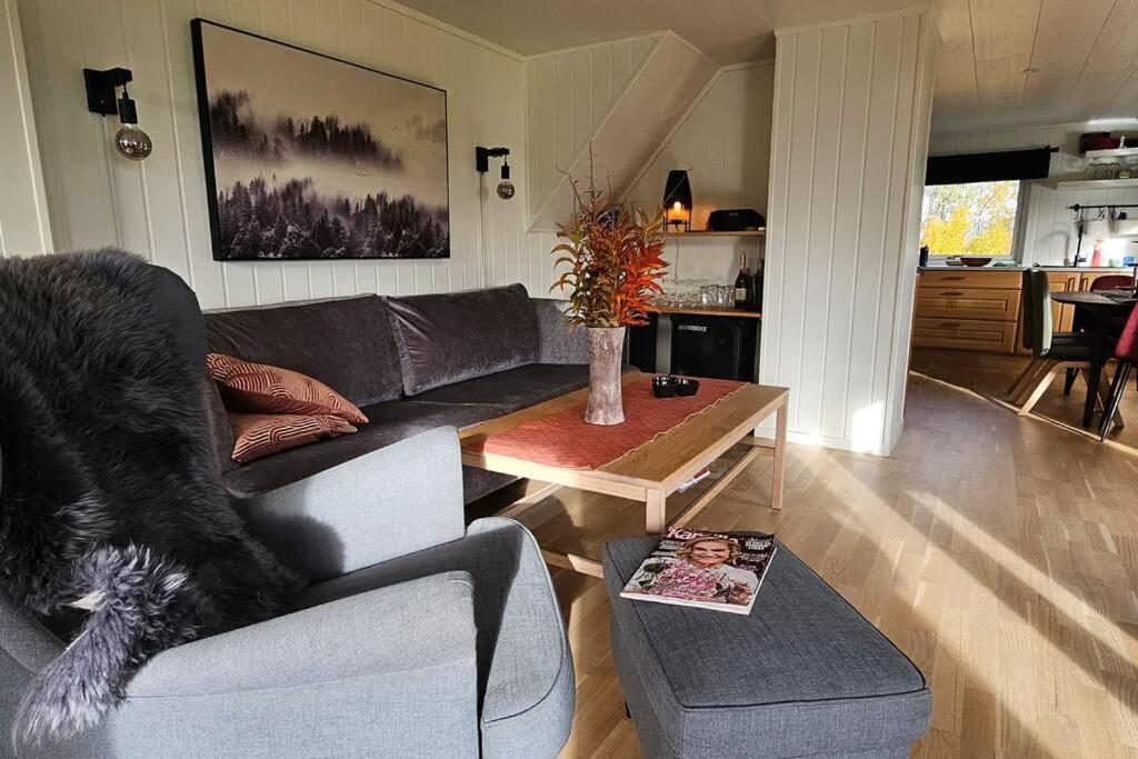 een woonkamer met een bank en een tafel bij Peaceful small house by the sea in Tromsø