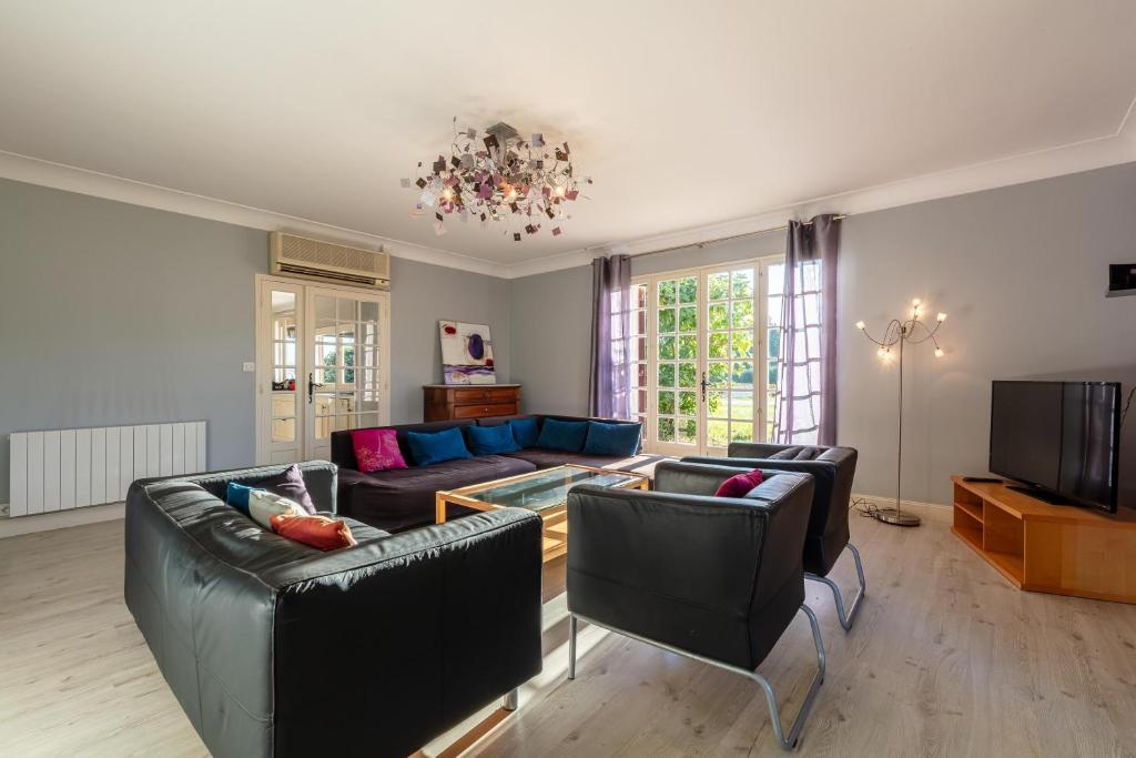 een woonkamer met 2 banken en een televisie bij Maison Carrosse - A 20min de Bordeaux in Martillac