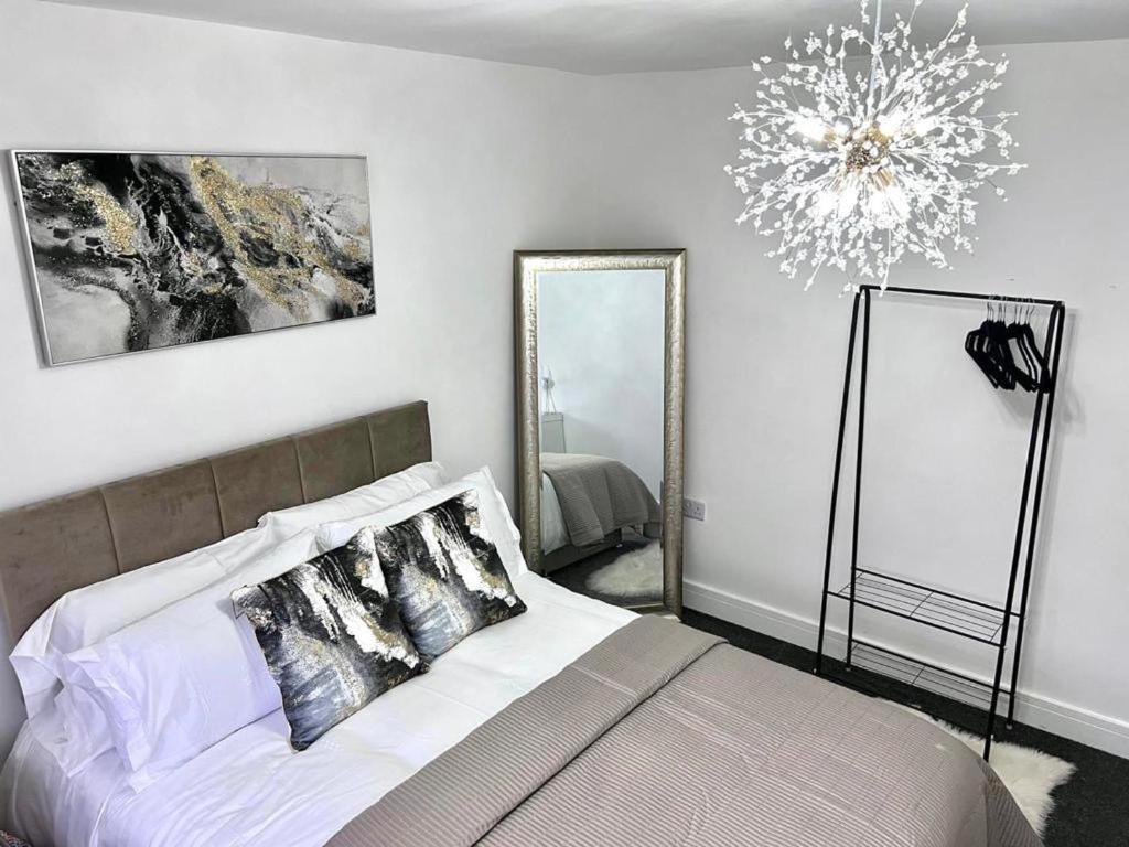 a bedroom with a bed with a chandelier and mirrors at Luxury 2-Bed Apartment Lindley Huddersfield in Huddersfield