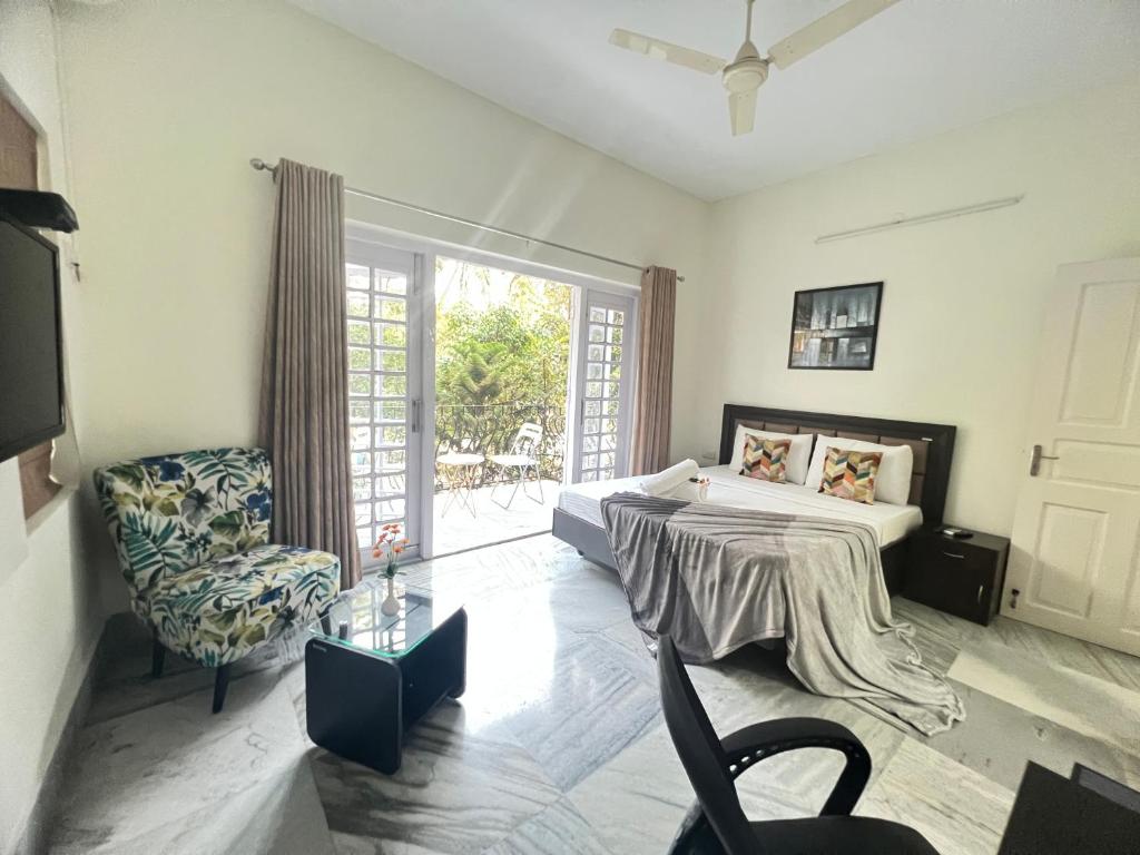 a bedroom with a bed and a chair and a window at Olive Serviced Apartments Salt Lake Kolkata in Kolkata