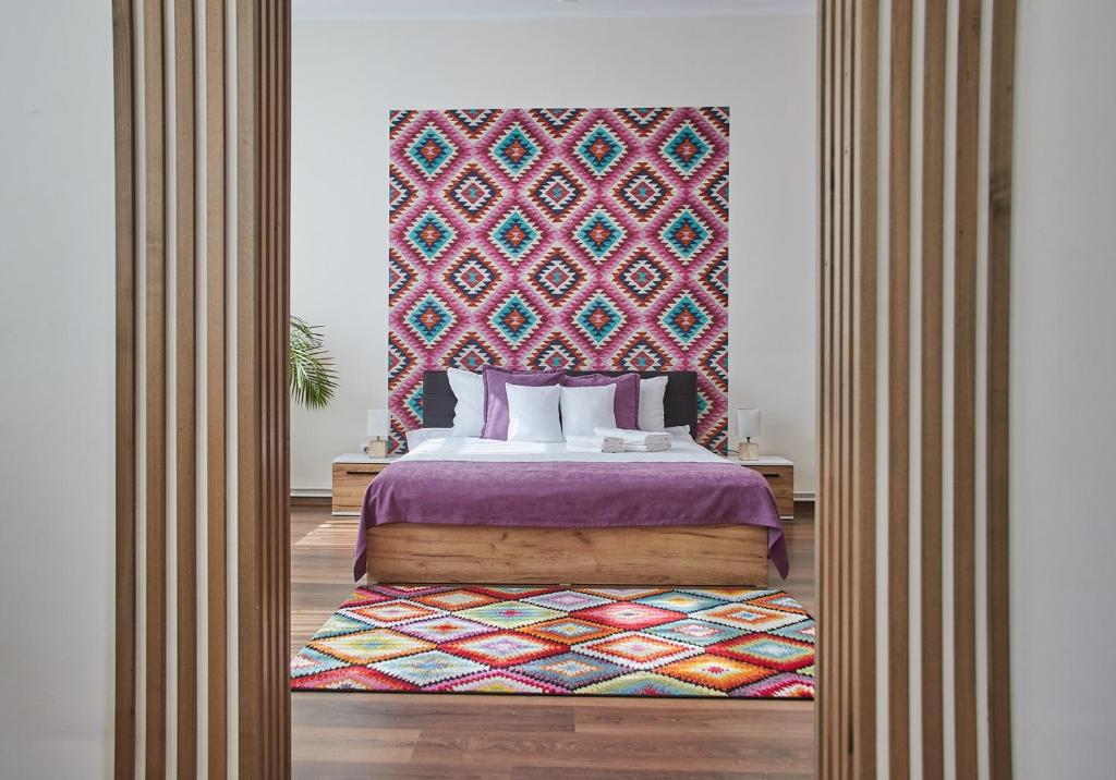 Dormitorio con cama extragrande y cabecero colorido en CONFORT HOUSE PLUS, en Alba Iulia