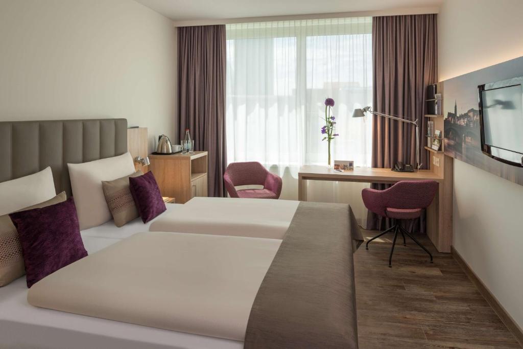 a hotel room with a large bed and a desk at Essential by Dorint Basel City in Basel