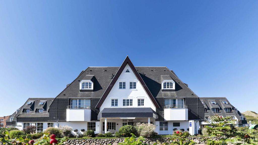 ヴェスターラントにあるDorint Strandresort & Spa Westerland/Syltの黒屋根の大白い家