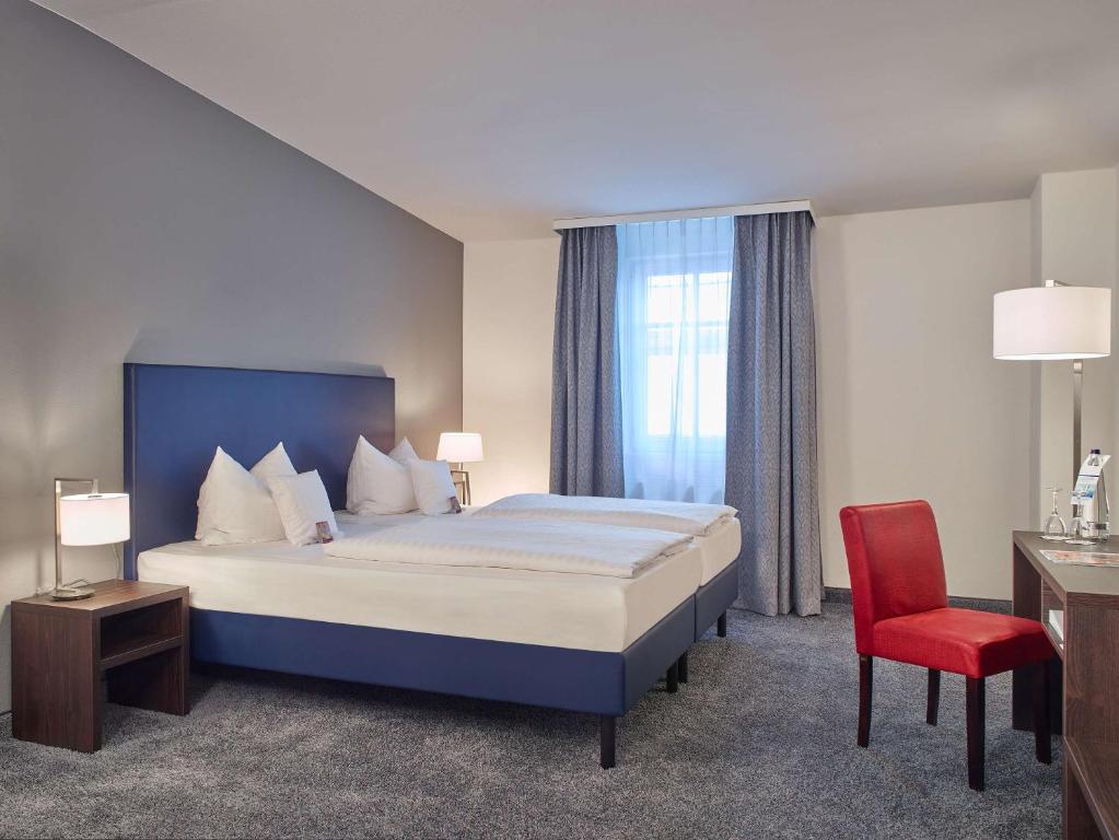 a hotel room with a bed and a red chair at B&K Hotels in Vlotho