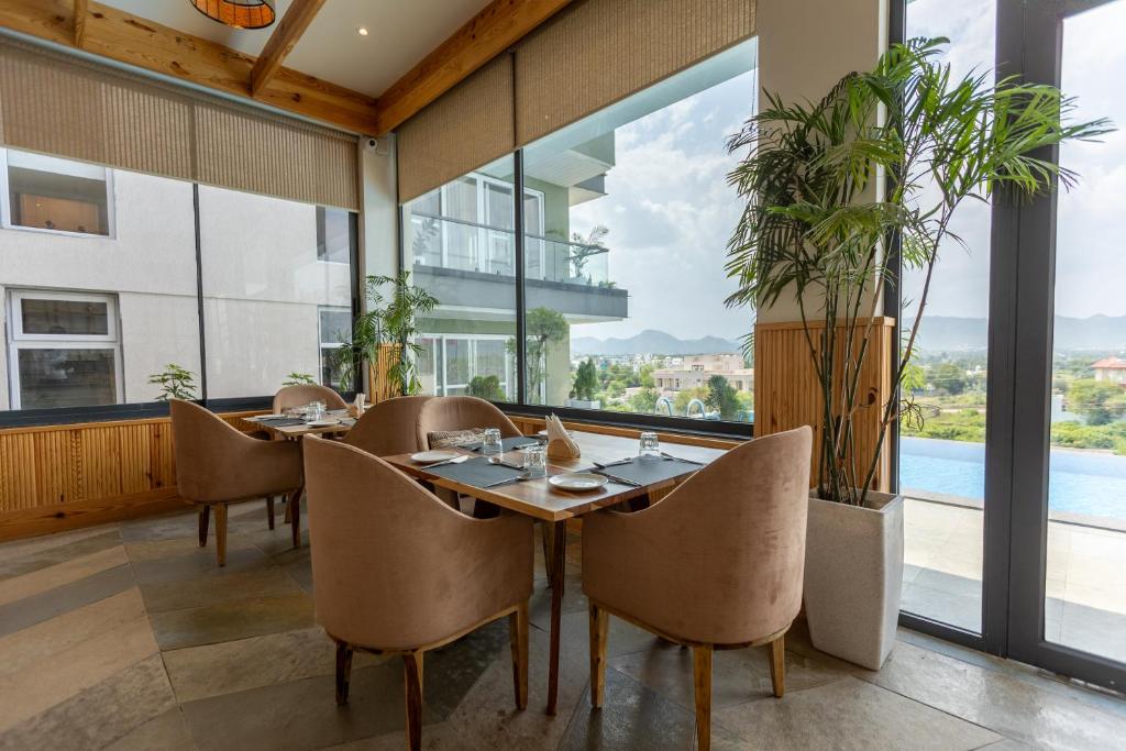 a dining room with a table and chairs and a large window at SURAMYA-A Luxury Boutique Hotel in Udaipur