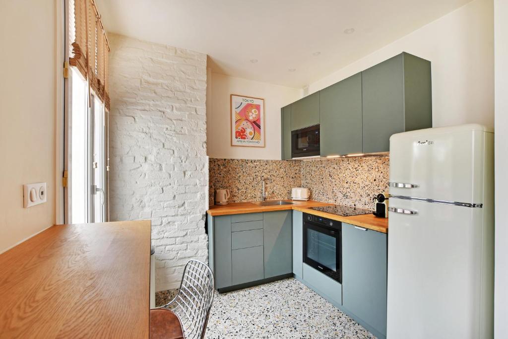 a kitchen with blue cabinets and a white refrigerator at Luxury Cocon by Les Maisons de Charloc Homes in Boulogne-Billancourt