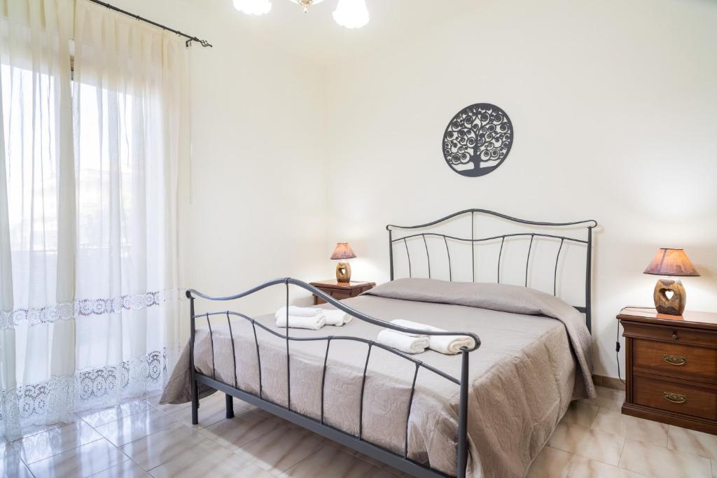 a white bedroom with a bed and a window at Monti Rossi Home Holidays in Nicolosi