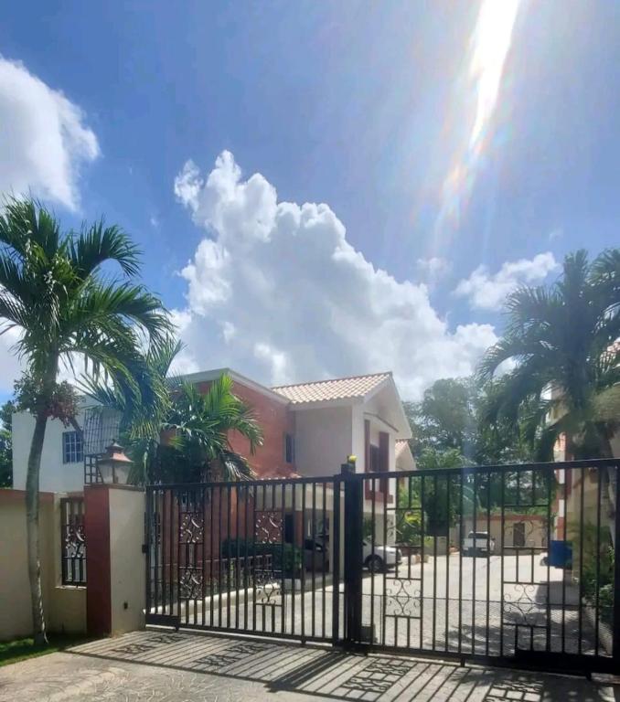 a gate in front of a house with palm trees at Cozy Apartment in La Romana