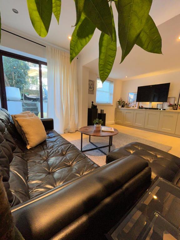 uma sala de estar com um sofá de couro e uma mesa em 2bed house in Vauxhall em Londres