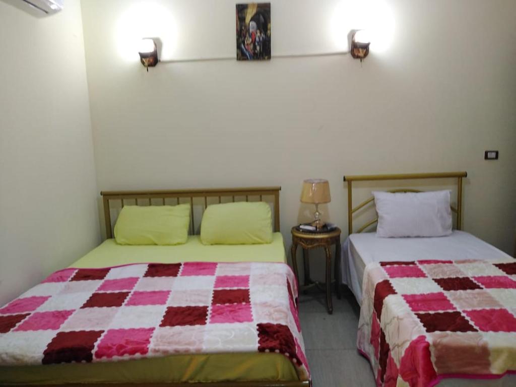 a bedroom with two beds and a table with a lamp at Cairo Lodge Hostel in Cairo