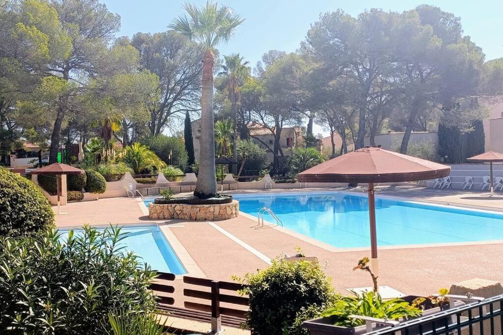 - une piscine avec une fontaine et un parasol dans l'établissement Bel appartement de standing à Boulouris, à Saint-Raphaël