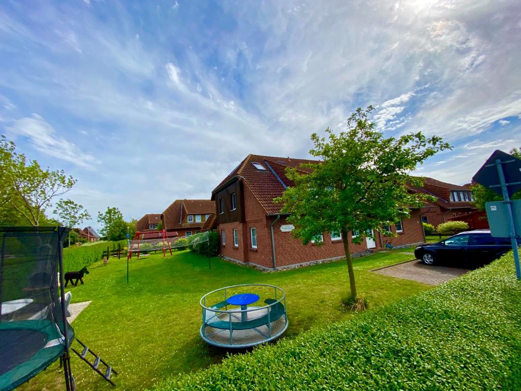 a house with a boat in a yard with a tree at Ferienwohnung Matschak OG links in Fehmarn