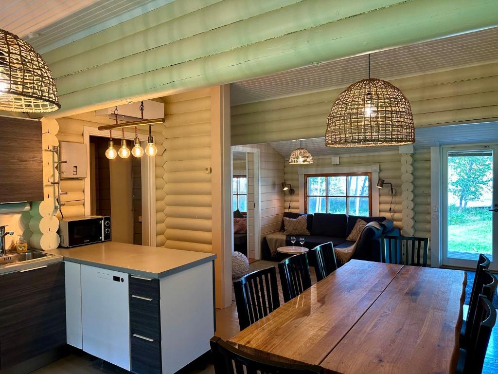 cocina y sala de estar con mesa de madera y sillas en Kuusiston majatalo, 