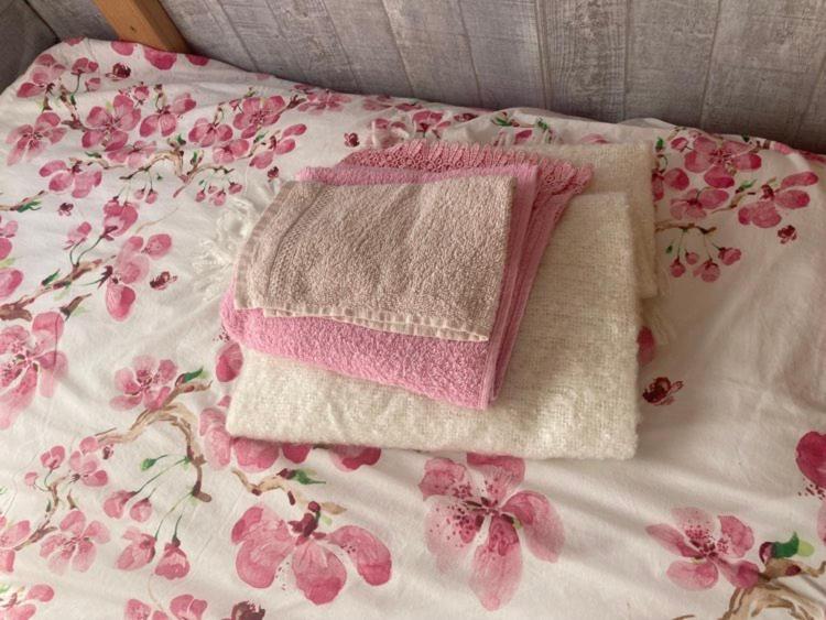 una coperta rosa e bianca con fiori su un letto di Tiny House Bohême pour amoureux en Day use 12 à 20H a Pont-à-Celles