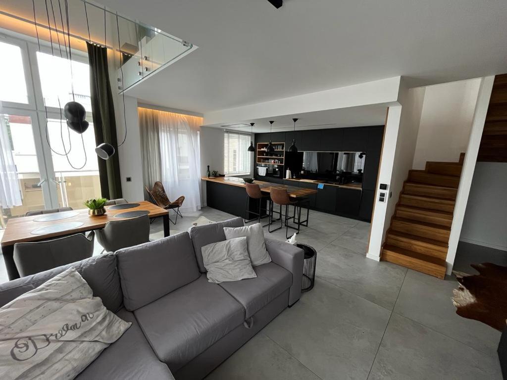 sala de estar con sofá gris y cocina en Luxury Apartments Słupsk en Słupsk