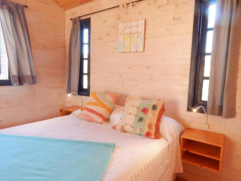 ein Schlafzimmer mit einem Bett und zwei Fenstern in der Unterkunft Ocean Paradise 1 in Punta Del Diablo