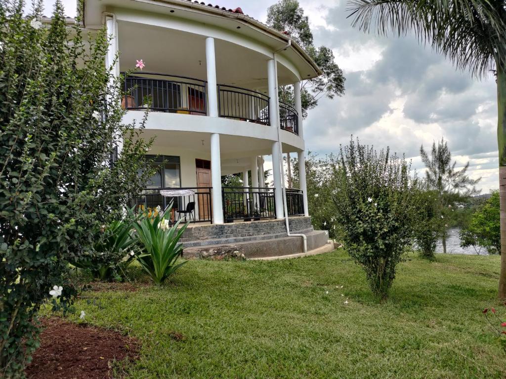 a large white building with a porch and a yard at Nile Retreat in Jinja
