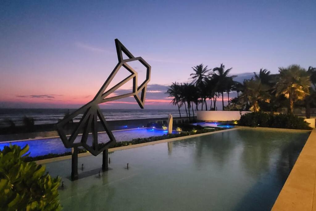 uma escultura de metal de uma mulher sentada em cima de uma piscina em Ikaroa Luxury apartment direct on the beach AirB&B em Acapulco