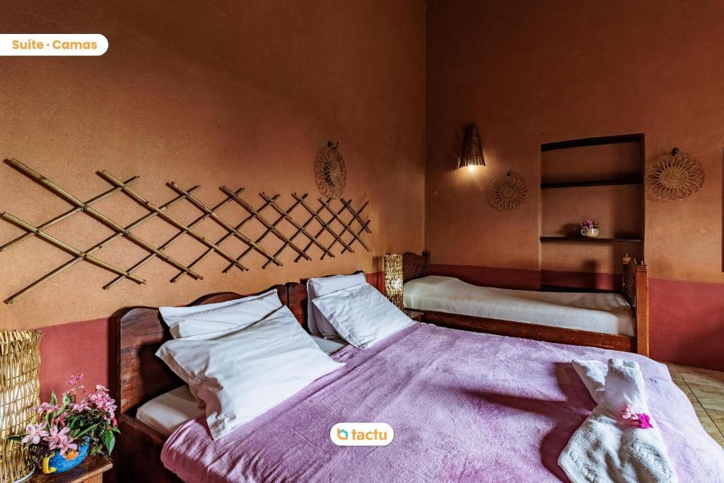 a bedroom with a bed with a purple blanket at Pousada Le Monte Cristo c/ Café Guaramiranga in Guaramiranga