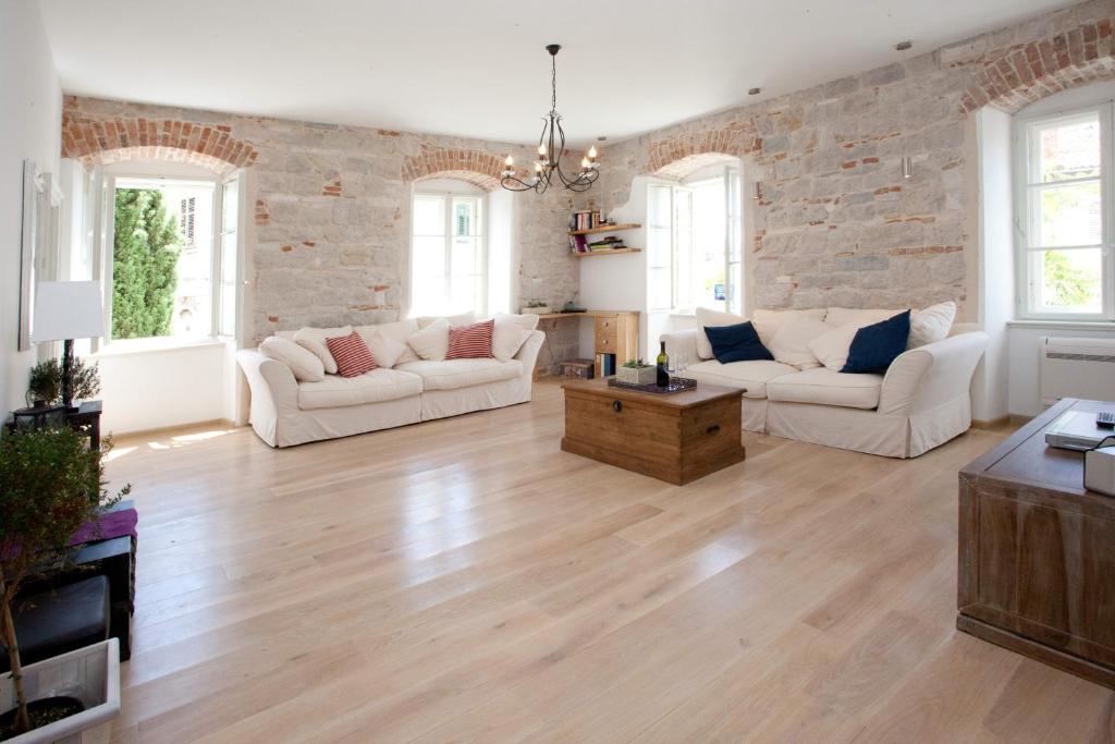 a living room with white furniture and a brick wall at Stylish Theatre Apartments in Split