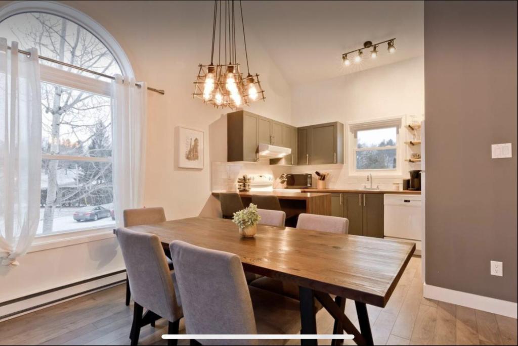 uma cozinha e sala de jantar com uma mesa de madeira e cadeiras em Cap Magog ! Près du lac Memphrémagog et Mont Orford em Magog-Orford