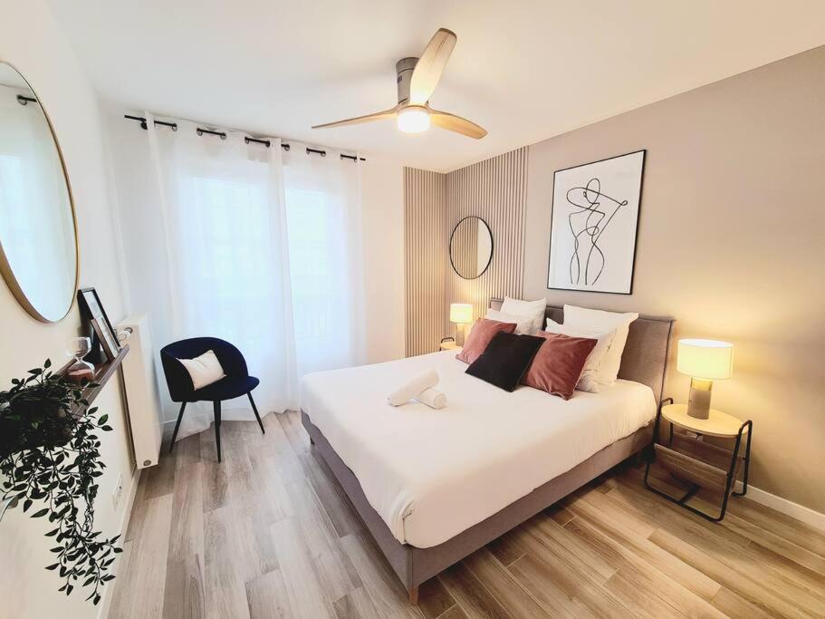a bedroom with a white bed and a black chair at *New* Céleste Appart 6 Pax 5 min Disney in Serris