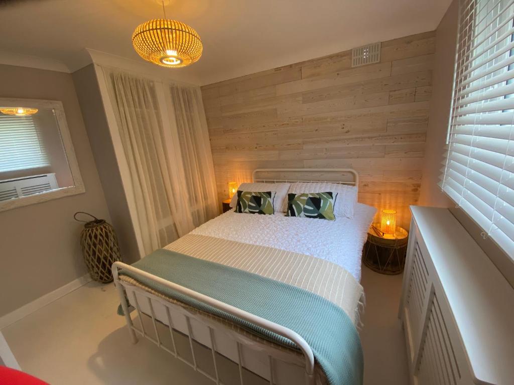 a bedroom with a bed with a wooden wall at Leeward Lodge in Totland