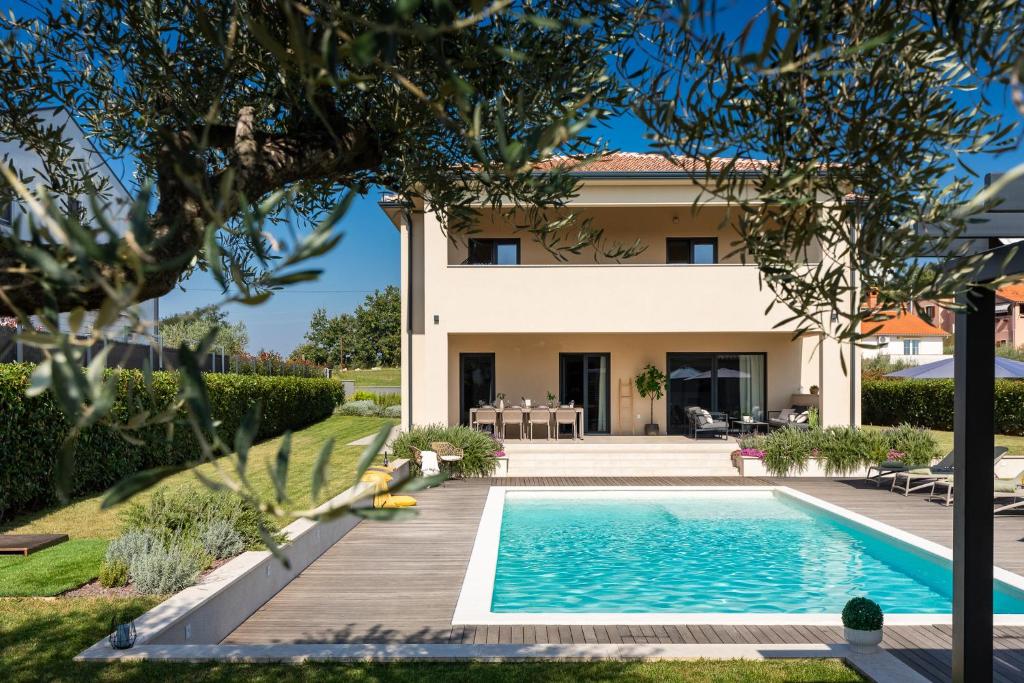 a villa with a swimming pool in front of a house at Modern villa Amoroso with pool in Porec in Nova Vas