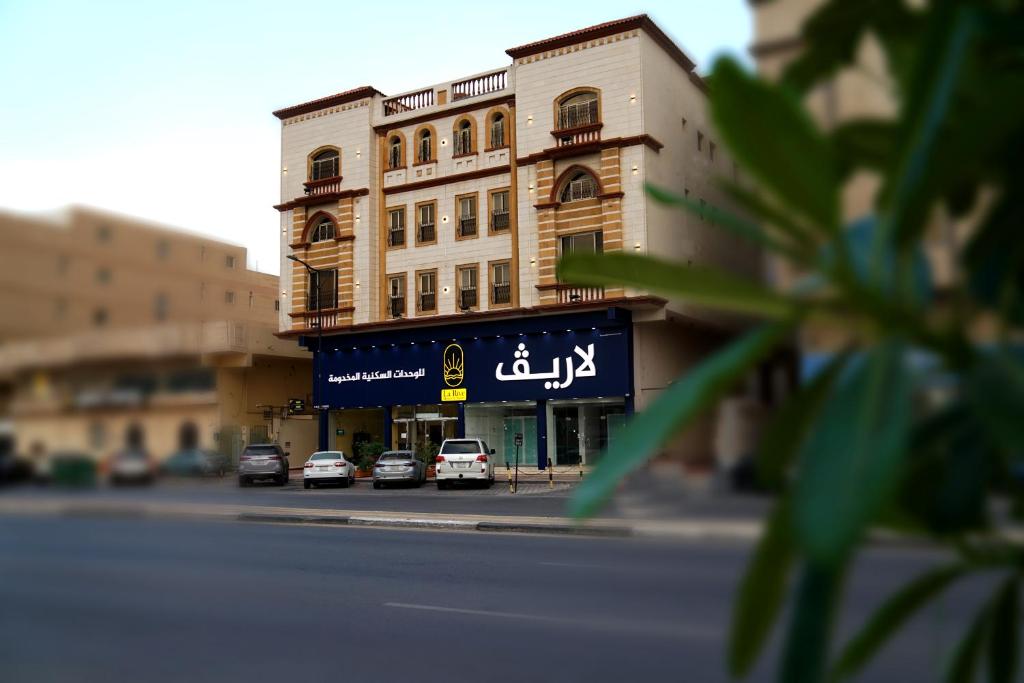 a building with cars parked in front of a street at La Rive Hotels & Suites in Dammam