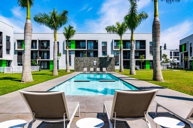 Ballito Luxury Apartment في باليتو: مسبح فيه كراسي و نخيل امام مبنى