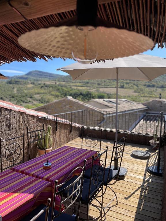 une table et un parasol sur une terrasse dans l'établissement Le Taurillou, à Taurize