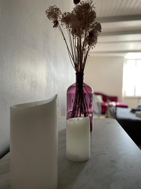 a vase with flowers and a candle on a table at Le Taurillou 