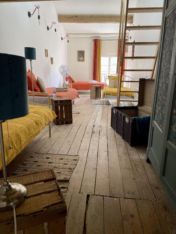 a living room with two beds and a wooden floor at Le Taurillou 