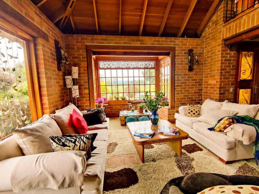 a living room with white couches and a brick wall at Casa Guaymaral. Encantadora, rural y espaciosa in Bogotá