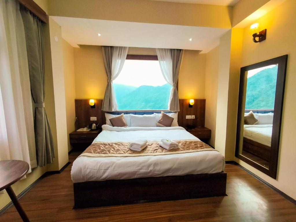 a bedroom with a large bed with a large window at Sila Norphel Pelling in Pelling