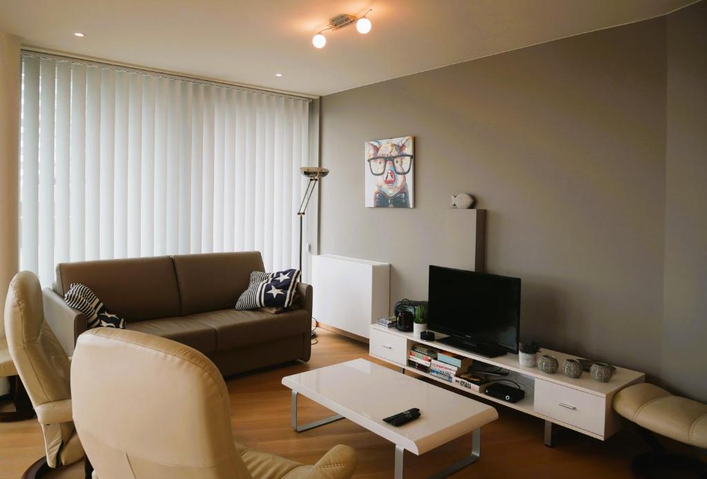 ein Wohnzimmer mit einem Sofa und einem TV in der Unterkunft Odyssey II 0203 in Bredene