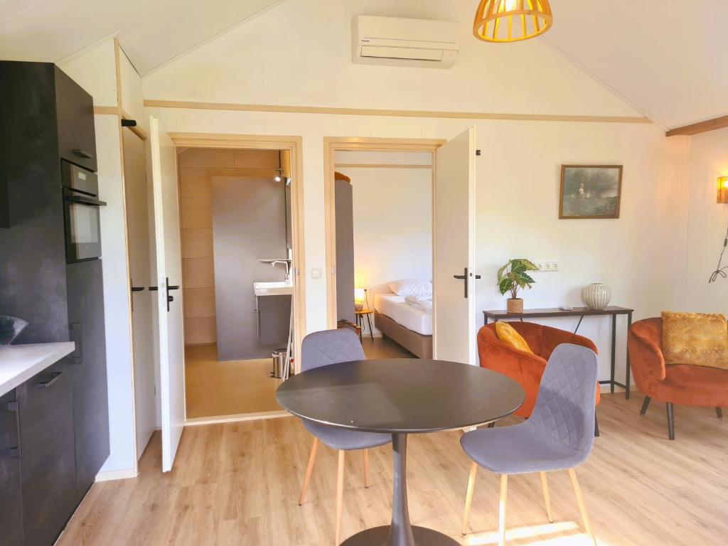 2-persoons luxe vakantiewoning في De Veenhoop: غرفة معيشة مع طاولة وكراسي وغرفة نوم