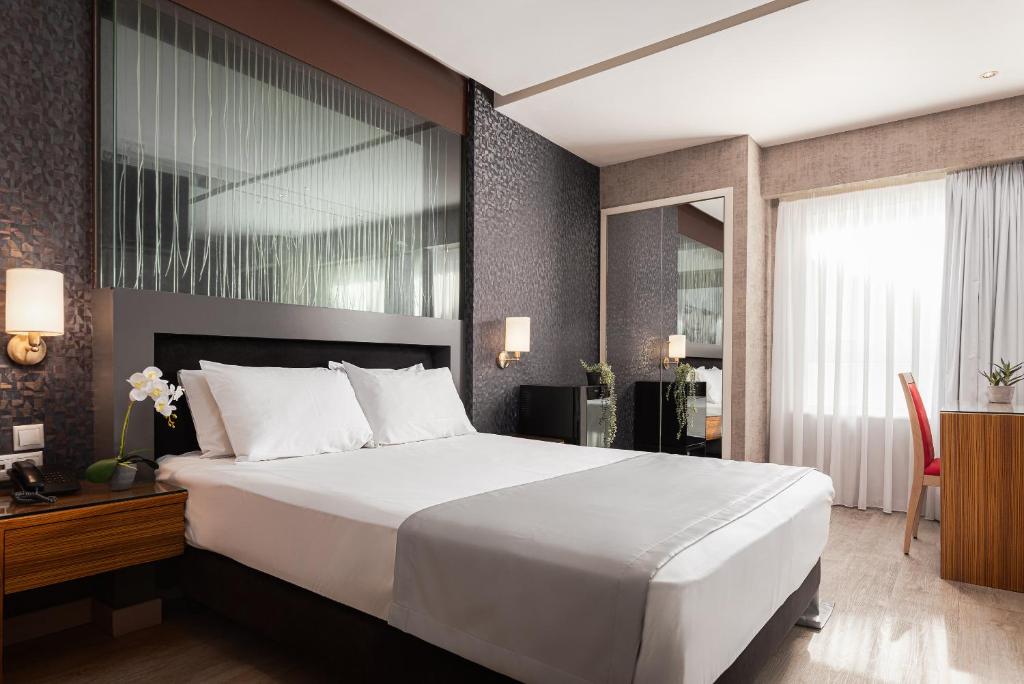 a bedroom with a large white bed and a desk at Lacoba Hotel in Athens