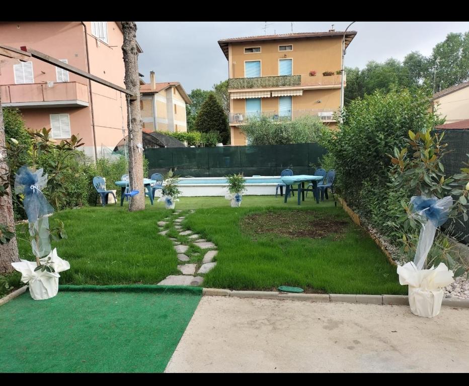 einen Hinterhof mit grünem Rasen mit Tisch und Stühlen in der Unterkunft Dante alighieri in Villa Colle Onorato