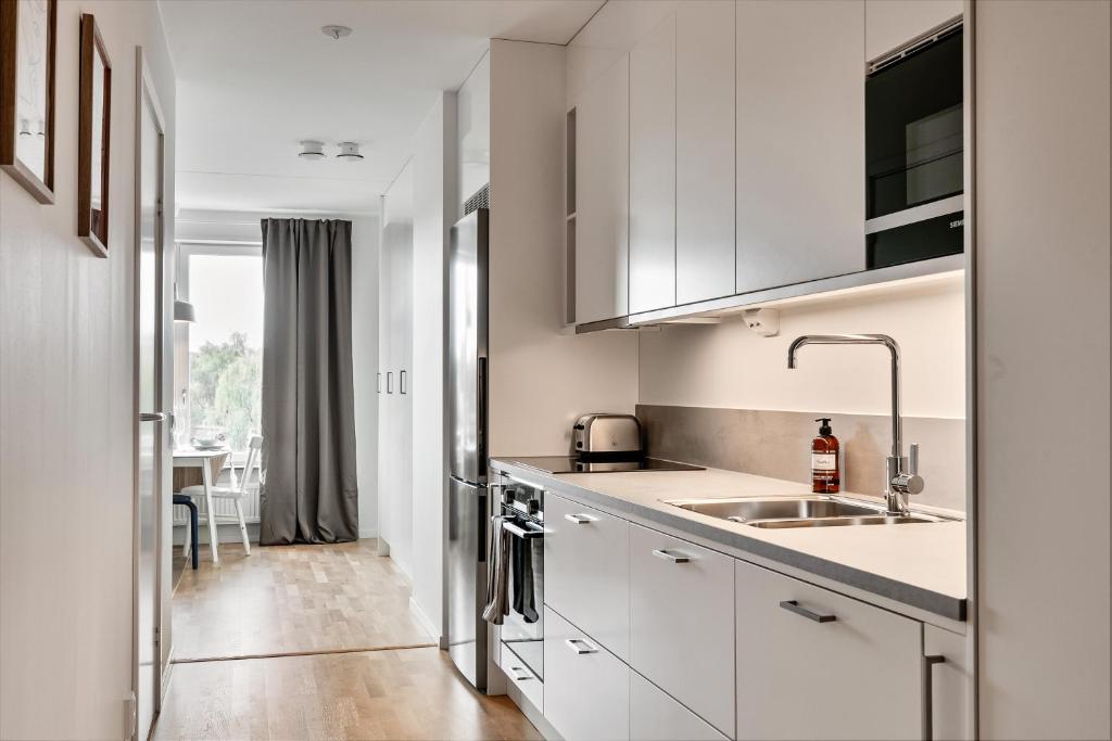 una cocina con armarios blancos y fregadero en Cosy Urban Home in Stockholm, en Estocolmo