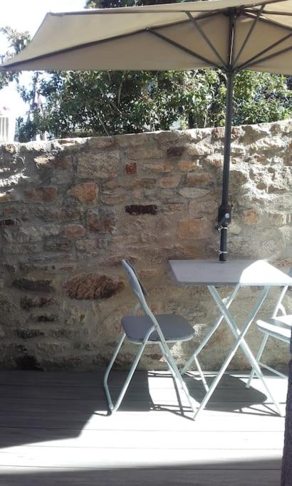 une table et une chaise sous un parasol dans l'établissement locmiquélic petite maison de pêcheur, à Locmiquélic