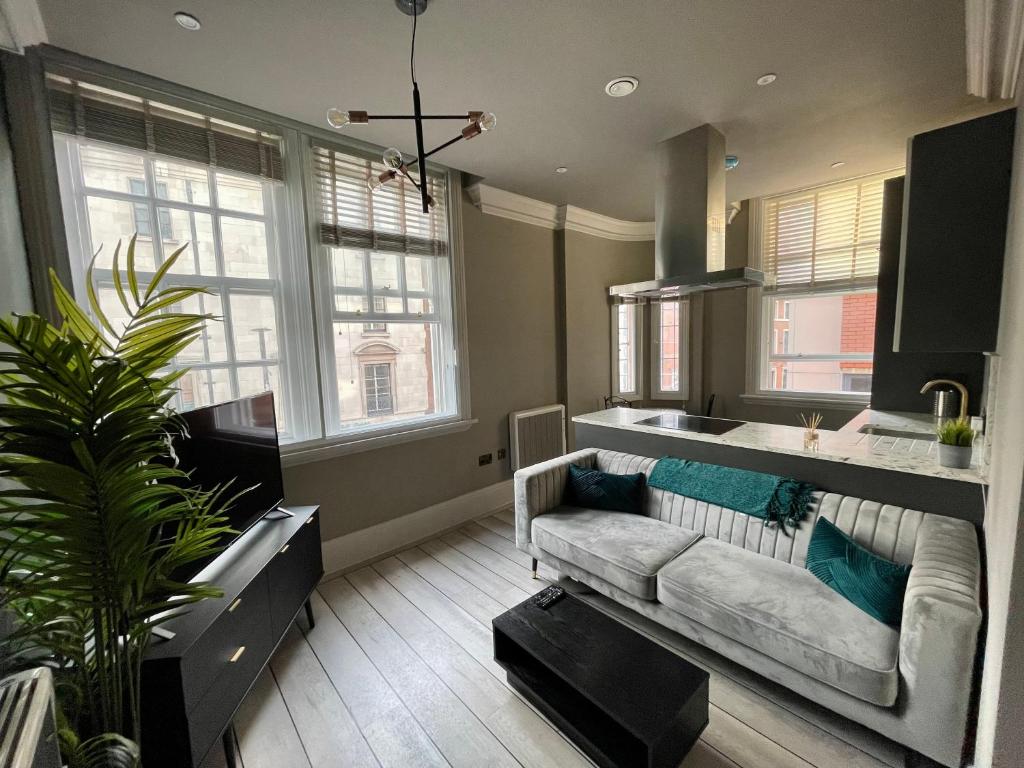 a living room with a couch and a kitchen with windows at Stylish En-suite in the heart of Manchester in Manchester