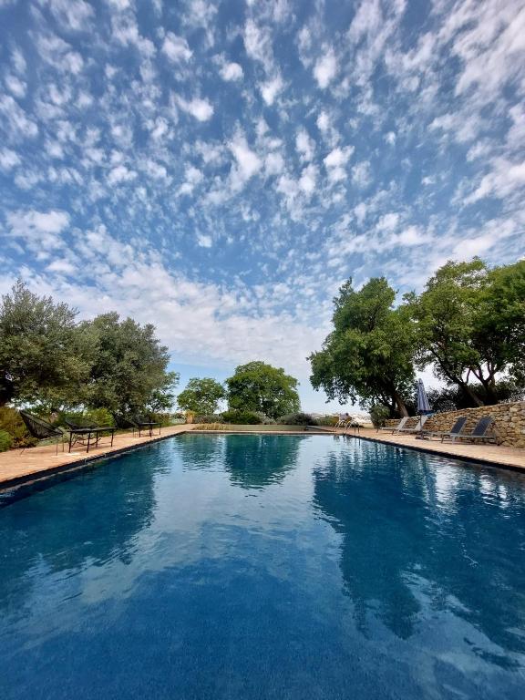 a large pool of blue water with a cloudy sky at Cortijo Bablou in Arcos de la Frontera
