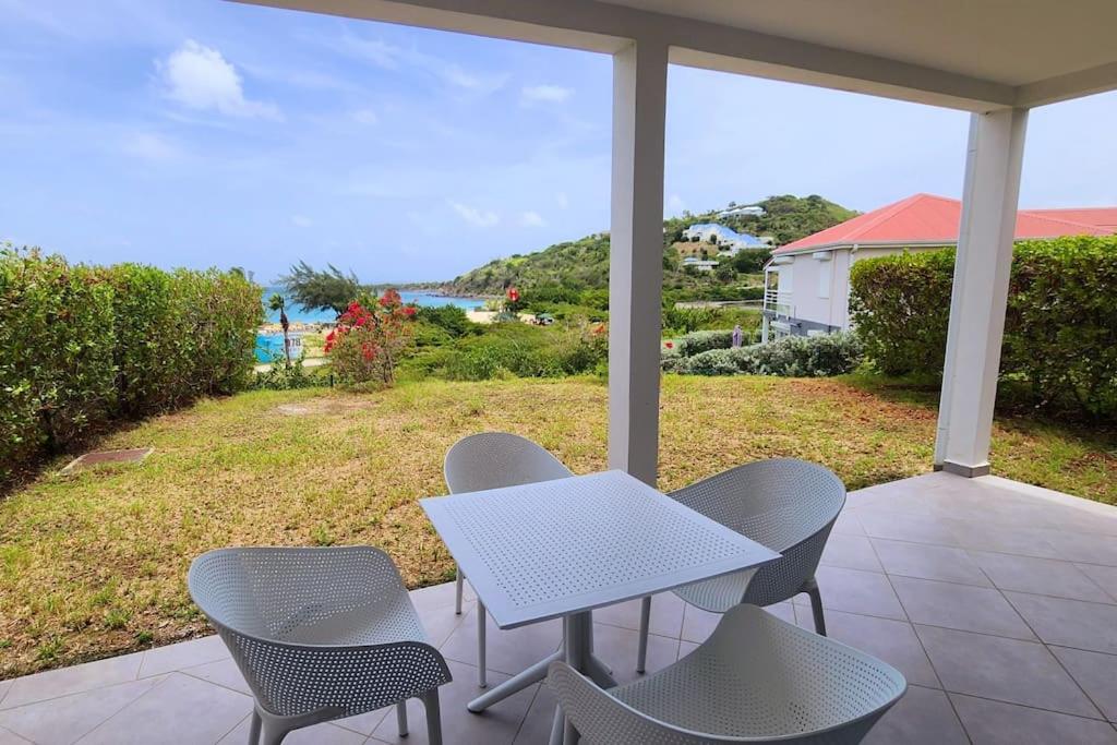 a table and chairs on a porch with a view of the ocean at Friar's beach - Luxurious unit by the beach in Saint Martin