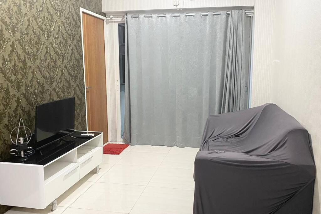 ein Wohnzimmer mit einem TV und einem Sofa in einem Zimmer in der Unterkunft Puncak Bukit Golf Apartemen in Surabaya
