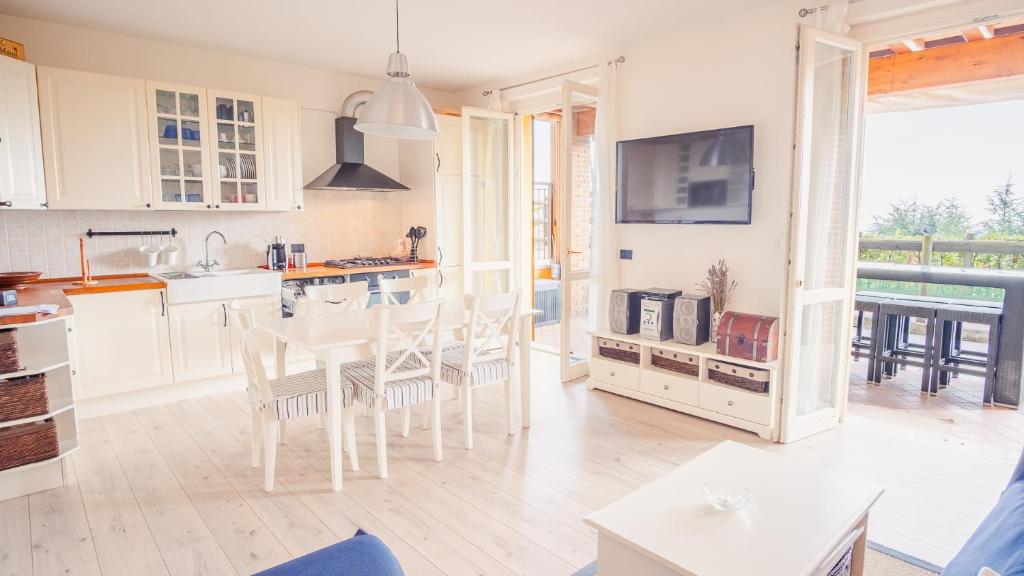 uma cozinha com armários brancos e uma mesa e cadeiras em La Terrazza sul Lago - Italian Homing em Polpenazze del Garda