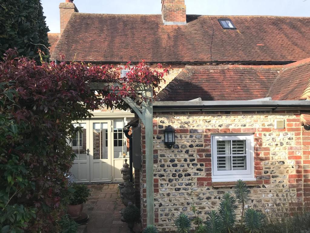 a stone house with a white door and a brick wall at Angel Cottage Cozy Nook in Boxgrove