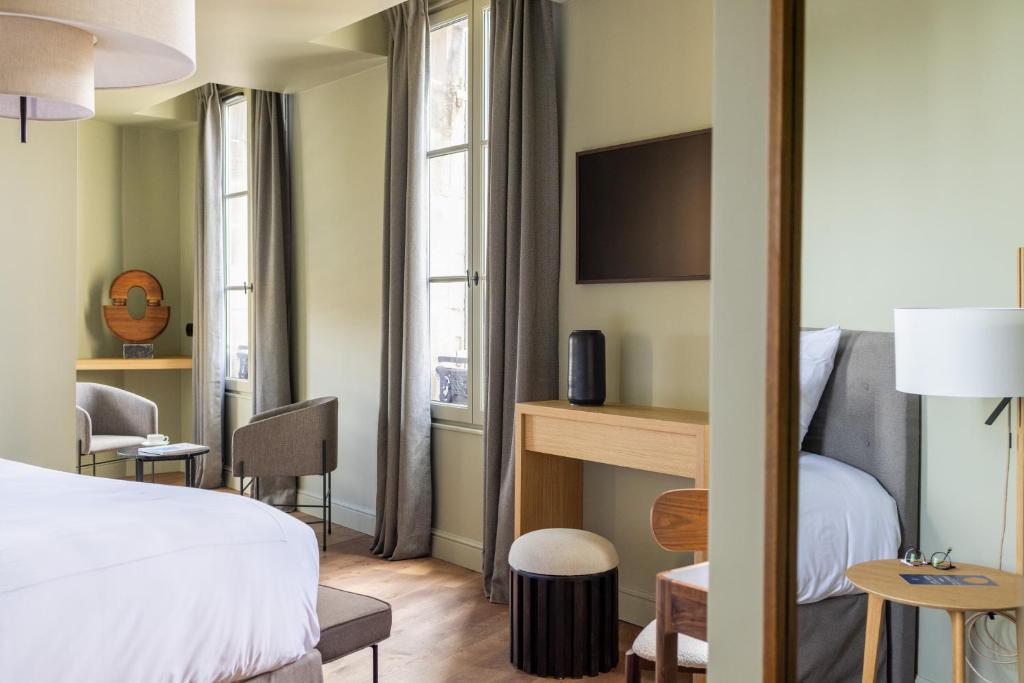 サン・テミリオンにあるHotel Porte Brunetのベッド、テーブル、椅子が備わるホテルルームです。