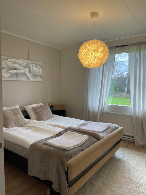 a bedroom with a large bed and a chandelier at Pieni omakotitalo joen rannalla in Rautio