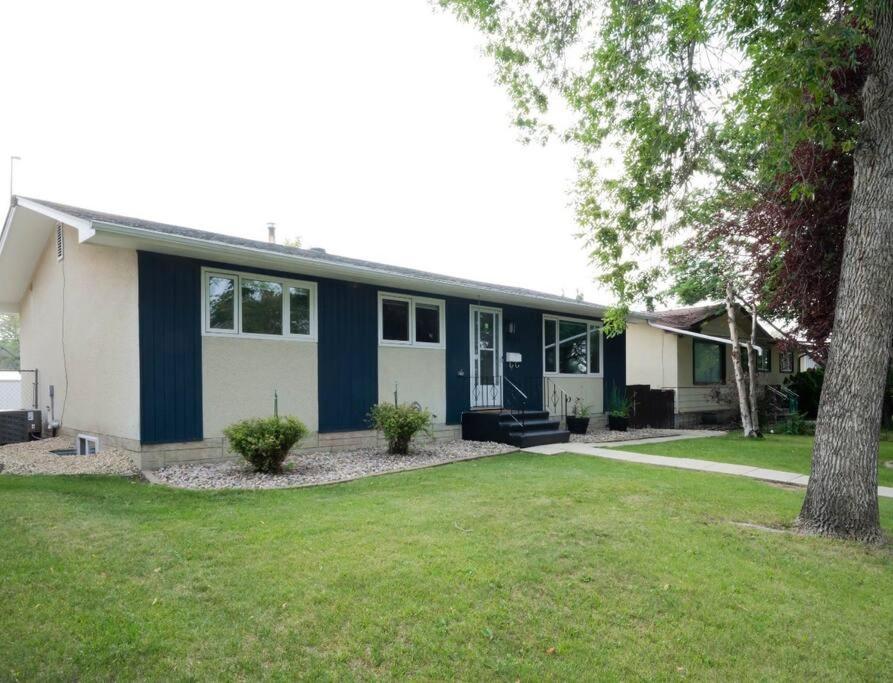 a blue and white house with a yard at 2BR 1BR cozy basement suite in Leduc